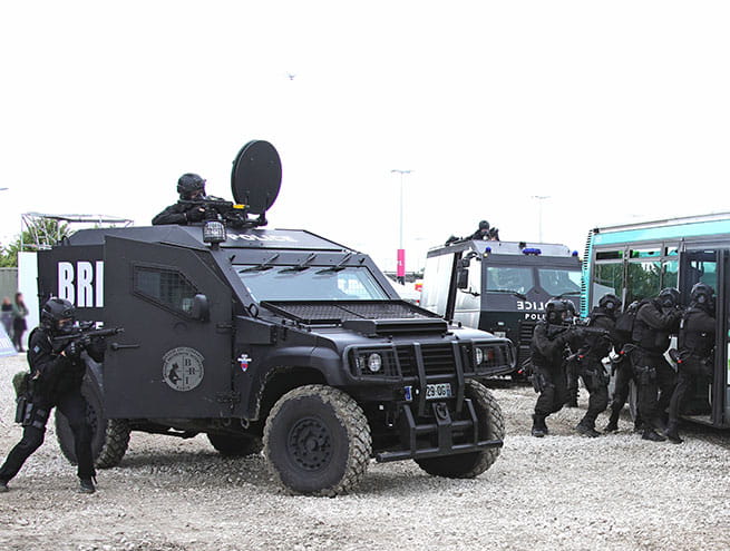 Un groupe de policiers de la brigade d'intervention (BI/DOPC) armés, en uniformes noir se tiennent à côté d'un véhicule BRI et s'introduisent dans un bus