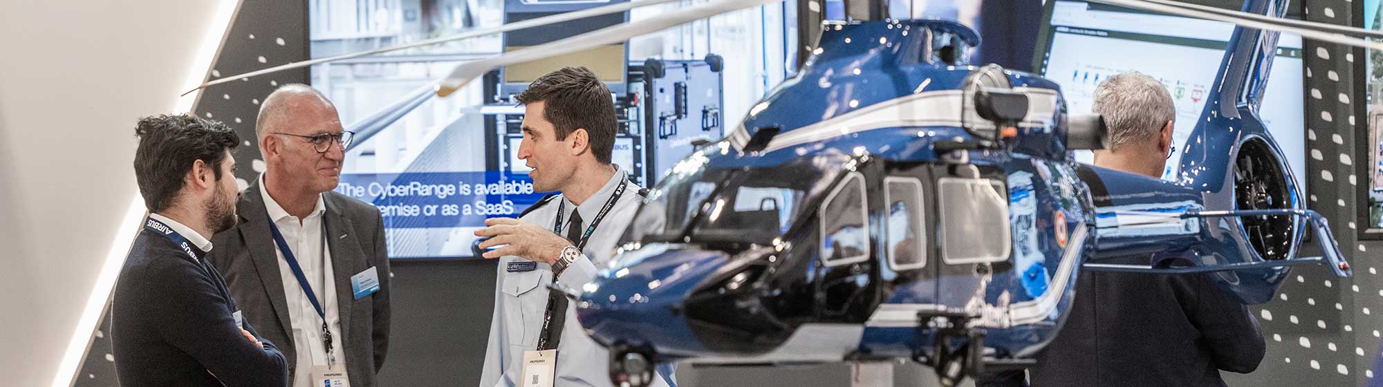 Group of men chatting on a stand with an helicopter exposed