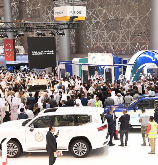 Vue du salon Milipol Qatar avec une foule de visiteurs et des véhicules