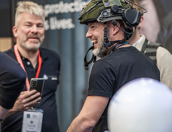 Un homme portant un casque rit avec d'autres exposants